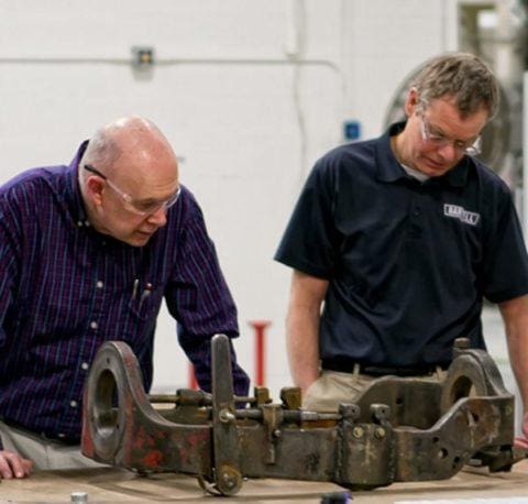 Two workers repairing parts on a machine
